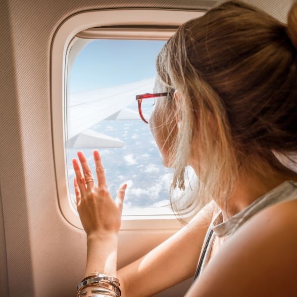 mulher olhando pela janela de um avião